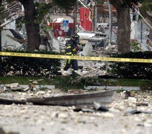 A firefighter walks through the remains of a building after an explosion. Several people were injured after a vacant pizza restaurant exploded in the South Florida shopping plaza Saturday, according to police. The restaurant was destroyed, and nearby businesses were damaged. (AP Photo/Brynn Anderson)